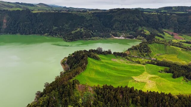 Volcanic lake Lagoa das Furnas surrounded by green hills and forest on Sao Miguel island, Azores. Natural landscape, aerial view