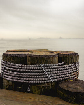 Weathered Wooden Pier Pilings Wrapped with Steel Cable by Foggy Waterfront