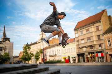 Skateboarder jumping high in urban city square © Zoran Jesic