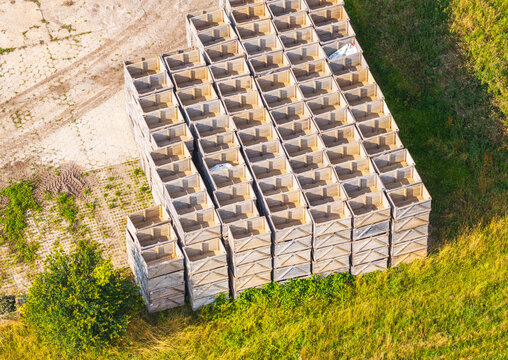 Aerial view of stacked wooden crates arranged in a large grid on a grassy field in Choczewo, Pomeranian Voivodeship, Poland.