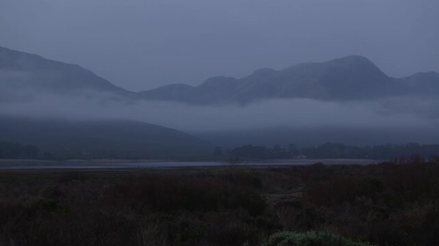 delicate fog hovering below Klein Mountains and lagoon and country road, Stanford, South Africa