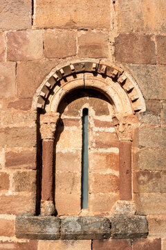 Detail of the 12th century Romanesque apsidal window with round arch, billet moulding, small shafts, and carved capitals in the ashlar wall of San Millan de Lara church, San Millan de Lara, Burgos