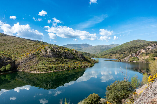 Embalse de Mansilla reservoir with reflections of sky and surrounding rocky hills in Mansilla de la Sierra, Sierra de la Demanda, La Rioja, Espana