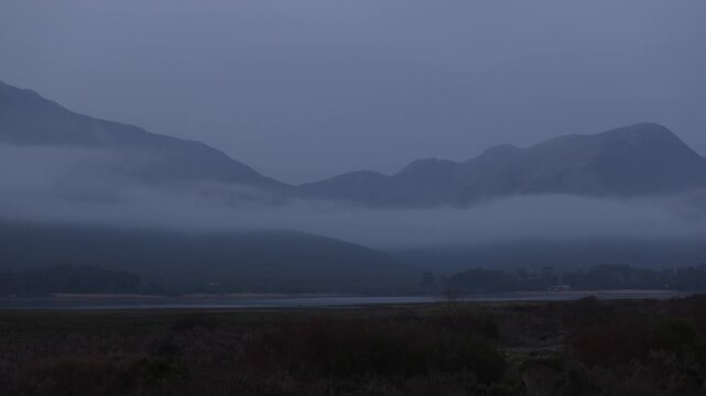 delicate fog hovering below Klein Mountains and lagoon and country road, Stanford, South Africa