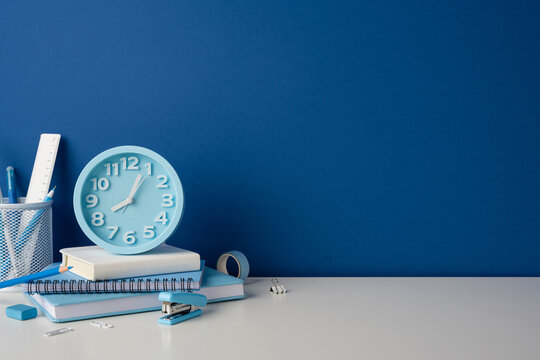 Side view photo of back to school desk with blue clock stationery and notebook
