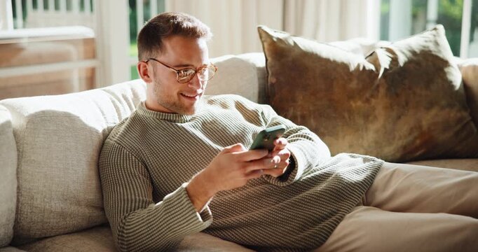 Text, glasses and man on sofa with phone, web search and online chat on social media app. Contact, eyewear and person in house with tech, internet browse and digital communication on virtual platform