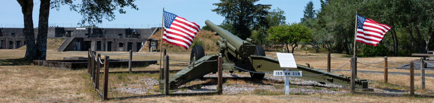 Large artillery gun and US flags at Historic military installation at Fort Stevens State Park, Hammond, Oregon Coast
