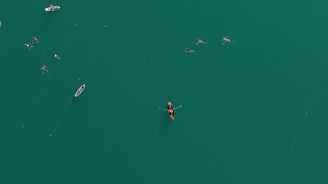 Top-down aerial view of swimmers, SUPs and row boats on Lake Bled, Slovenia