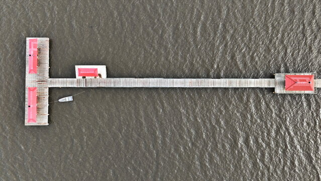Aerial view of the Sabana de la Mar pier featuring red-roofed structures and a small boat moored in the water in Sabana de la Mar, Hato Mayor Province, Dominican Republic.