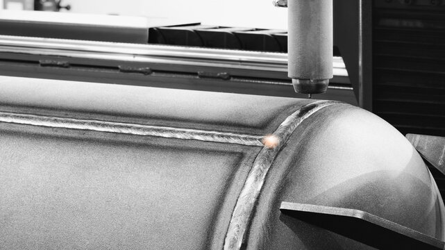 Close-up of modern industrial welding machine with fixed pipe with weld seam, tech industrial technology background