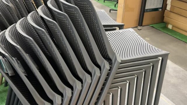 A collection of gray plastic chairs is presented in an organized retail display, allowing shoppers to compare durable and lightweight outdoor seating for home and garden spaces. Close up.