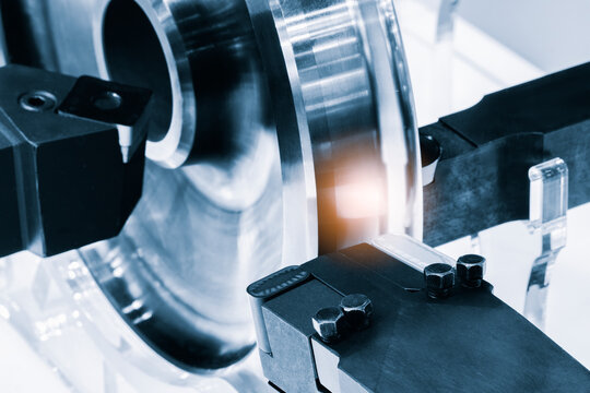 Close-up of a metal cylindrical shaft in a grinding process. Black machine components hold the metal securely. reflective surface shows material's smooth finish, tech industrial technology background