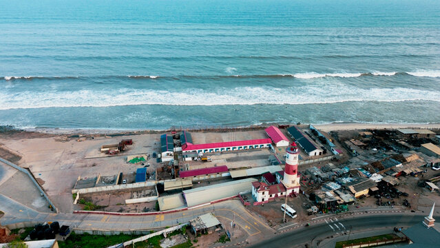 Aerial view of the historic Jamestown Lighthouse standing near the coastline with surrounding buildings, roads, and the Atlantic Ocean in Accra, Greater Accra Region, Ghana.