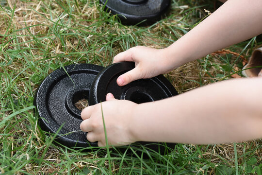 A toddler is grabbing a weight plate
