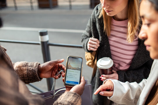 Travelers booking a historic walking tour on smartphone in city