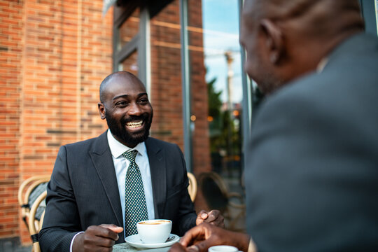 Two businessmen meeting over coffee at outdoor cafe