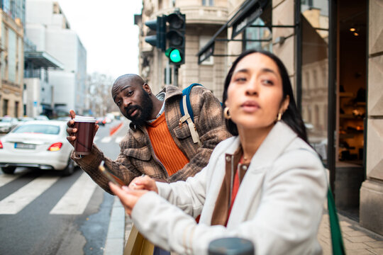 Two friends waiting at city crosswalk with coffee cups