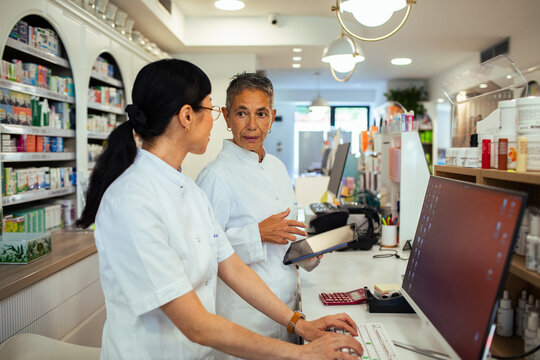 Two pharmacists collaborating at computer in modern pharmacy