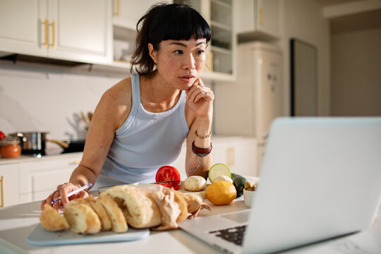 Woman following online recipe while cooking in home kitchen