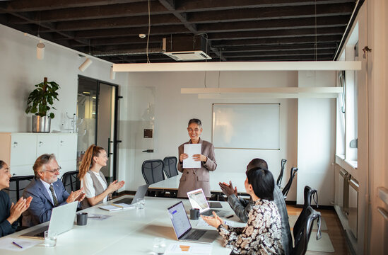 Diverse business team applauding leader in office meeting