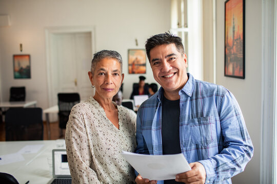 Two coworkers smiling with paperwork in coworking office