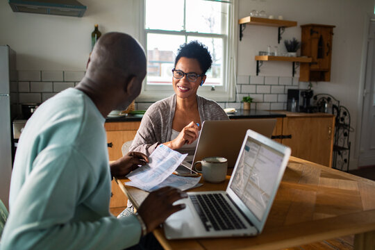 Smiling couple planning finances at kitchen table