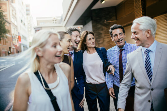 Smiling business colleagues walking together in city street
