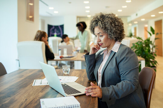 Senior businesswoman working on laptop in modern open office