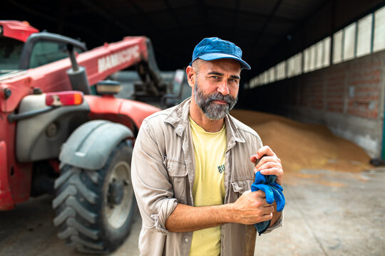 Bearded farmer with telehandler in grain storage barn