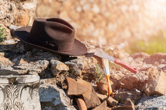 Archaeologist brown hat and brush resting on ancient stone ruins at excavation site