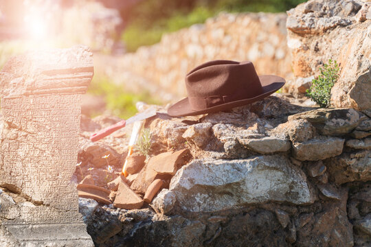 Archaeologist brown hat and brush resting on ancient stone ruins at excavation site