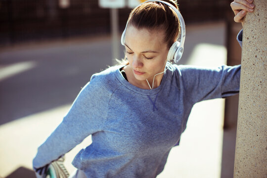Young woman stretching with headphones on city street