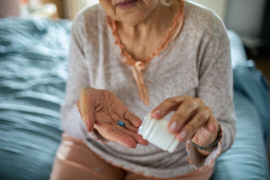 Senior woman taking prescription pill at home