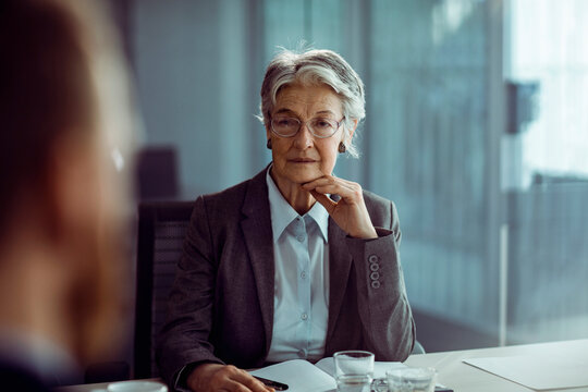Senior businesswoman listening during meeting in modern office
