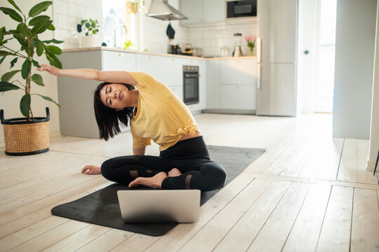 Young woman practicing online yoga in home kitchen