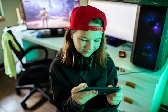 Teen girl gaming on smartphone at home desk