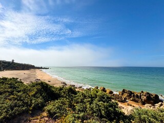 Low-lying coastal fog drifts across the Cala de Encendida against a blue sky, Roche, Novo Sancti Petri, Chiclana de la Frontera, Andalusia, Spain © keBu.Medien