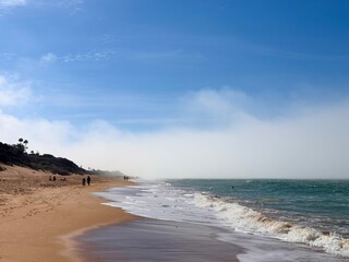 Low-lying coastal fog drifts across the beach of Playa de Roche against a blue sky, Roche, Novo Sancti Petri, Chiclana de la Frontera, Andalusia, Spain © keBu.Medien