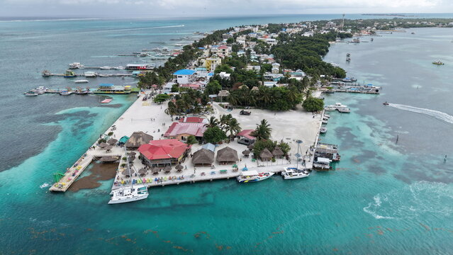 Aerial view of Caye Caulker with turquoise Caribbean waters, docks, boats, and tropical buildings on the island in Belize.