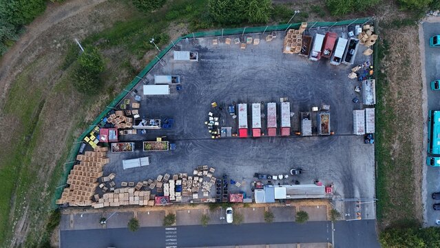 Aerial view of the Iron Mountain Data Centers FRA-2 logistics yard featuring numerous wooden pallets, shipping containers, and parked trucks in Frankfurt am Main, Hessen, Germany.