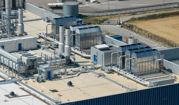 Aerial view of industrial cooling towers, HVAC systems, and process piping on the rooftop of a semiconductor manufacturing facility in Crolles, Auvergne-Rhone-Alpes, France.