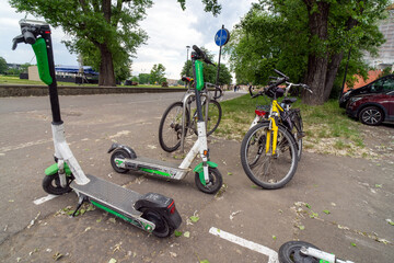 Several bicycles and electric scooters parked together. These modes of transportation are used for active travel on campuses and in cities. E-scooters, rental option in cities. To rent and park.  © Jacek