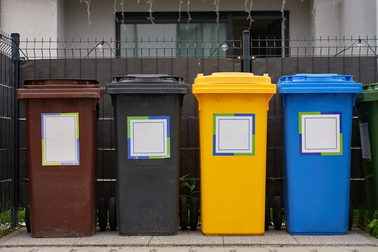 Row of recycling bins for different types of household waste stands outside residential property