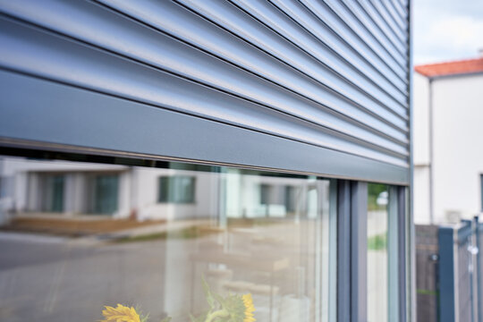 Exterior roller shutter is lowered over the upper part of modern residential window