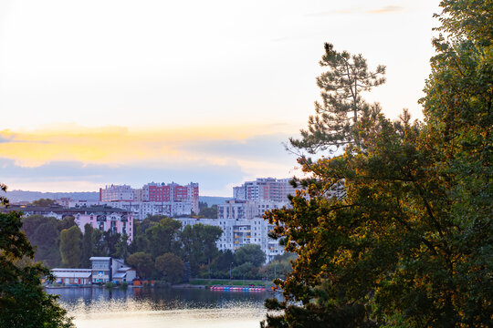 Horizontal cityscape of residential apartment buildings near a lake and park at sunset
