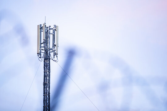 Telecommunication 5G cellular network tower against pastel sky background with copy space