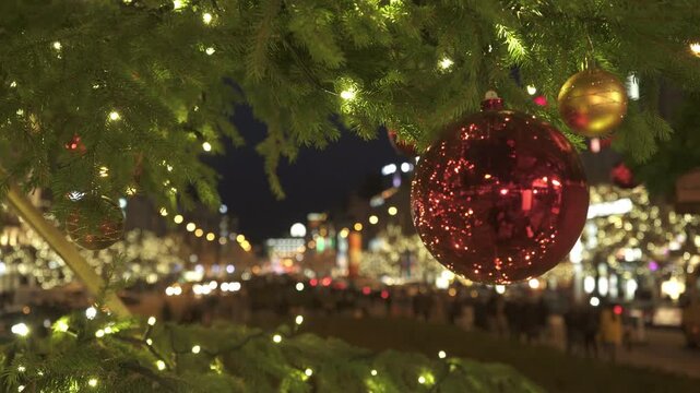 Illuminated outdoor Christmas tree decorated with red and gold baubles fairy lights twinkle in Prague night. low-angle view looking up into the dense pine branches