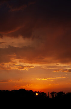 Vertical shot of dramatic fiery sunset with storm clouds. Beautiful vertical composition. Clean scenic twilight background with realistic natural textures.