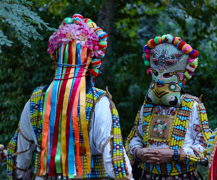 Close up of traditional pagan carnival masks and decorated clothing, Balkan folklore. Bulgarian Kuker performers in colorful costumes with masks in a forest setting during a traditional ritual