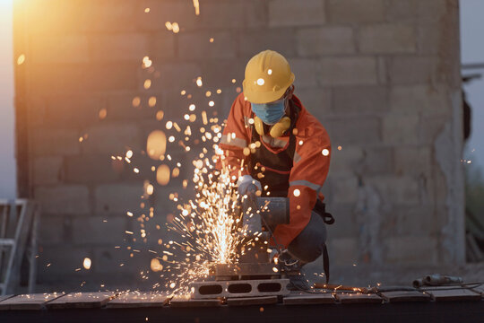 Close-up of a Welder in protective workwear using an angle grinder on a construction site, Thailand